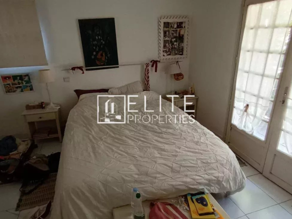 Chambre d'une maison de plain-pied à rénover, avec un lit et des fenêtres donnant sur l'extérieur.