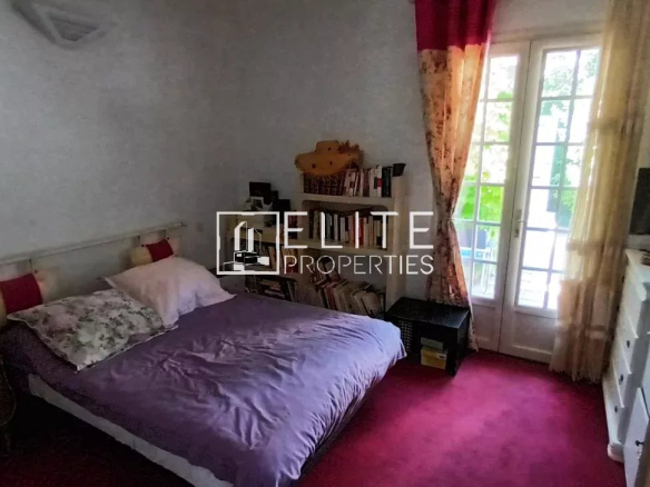 Chambre d'une maison de plain-pied à Mougins avec lit, bureau et accès à l'extérieur.