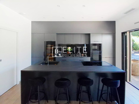 Modern and fully equipped kitchen with a central island and black stools in a villa in Vallauris.