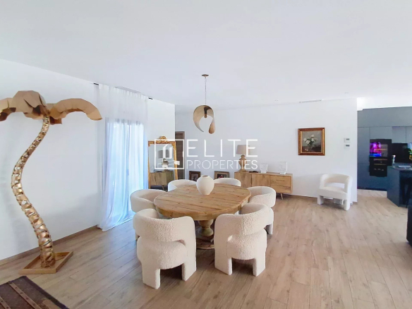 Modern dining room with wooden table and white chairs in a renovated villa in Vallauris.