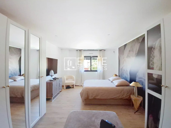 Spacious room with double bed and modern decor, windows overlooking the outside.