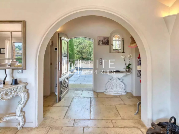 Interior of a villa with an arch, stone floor and access to the outside.