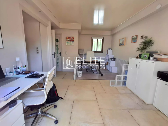 Interior of a bright office in a modern villa with white furniture and a view of the garden.