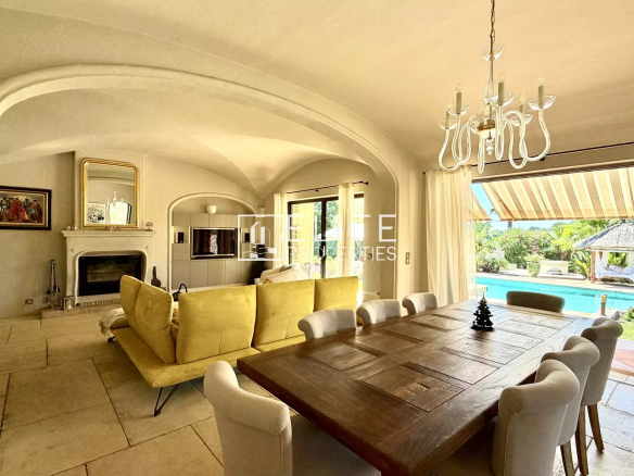 Interior of a villa with living room and dining room, overlooking the pool and garden.