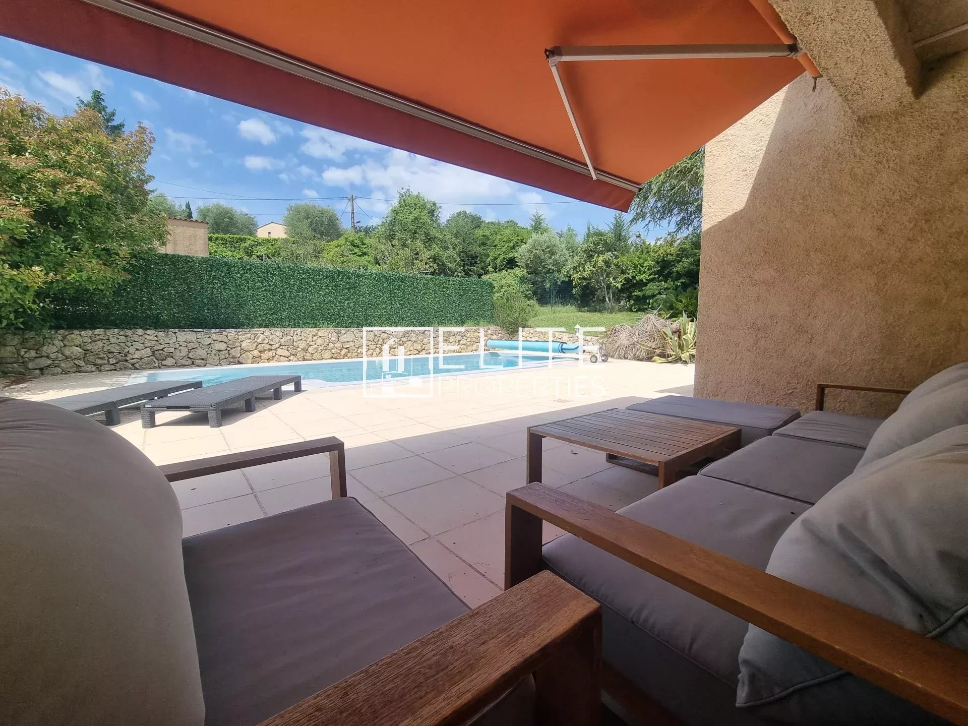 Terrasse avec fauteuils et vue sur la piscine dans une maison de plain-pied à Grasse.