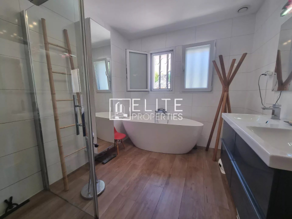 Salle de bain moderne avec baignoire, douche et lavabo dans une maison rénovée.