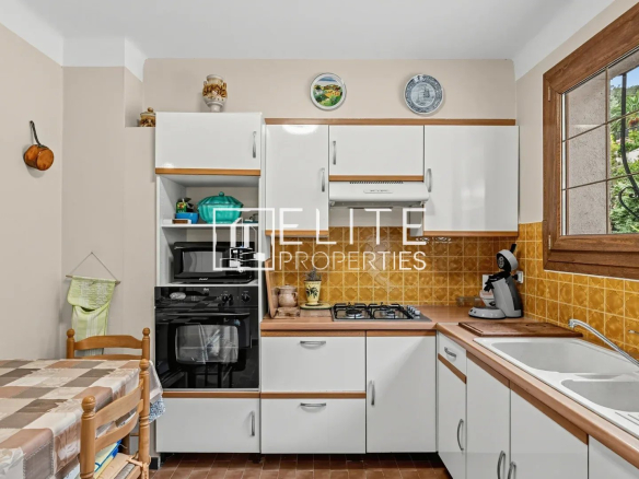 Cuisine d'une maison à rénover à Mandelieu-la-Napoule, avec meubles blancs et carrelage jaune.