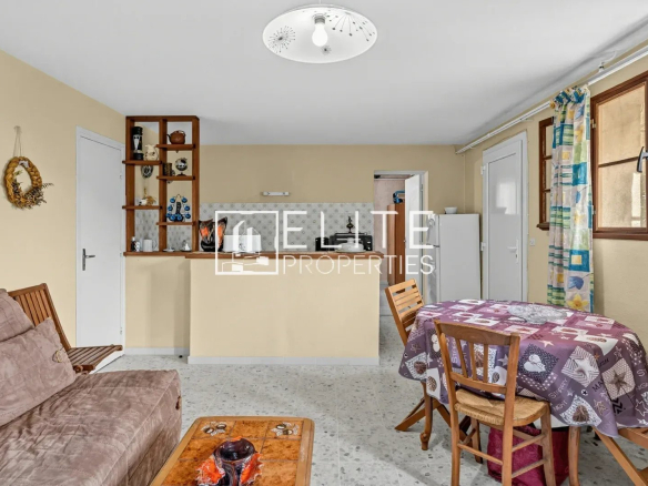 Intérieur d'une maison à rénover avec un salon, une table et des chaises.