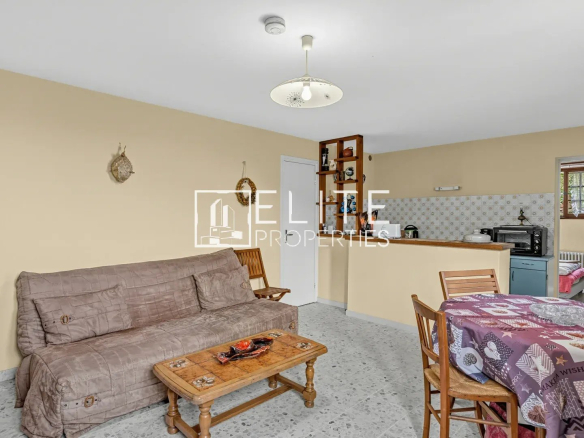 Intérieur d'une maison à rénover avec salon et salle à manger, murs clairs et mobilier simple.