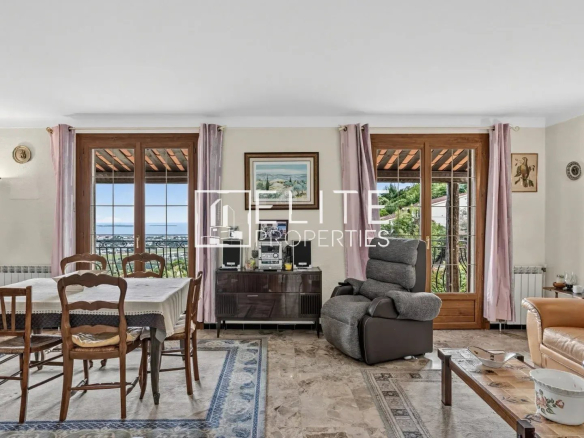 Intérieur d'une maison à rénover avec vue sur la mer, salon et salle à manger, mobilier varié.