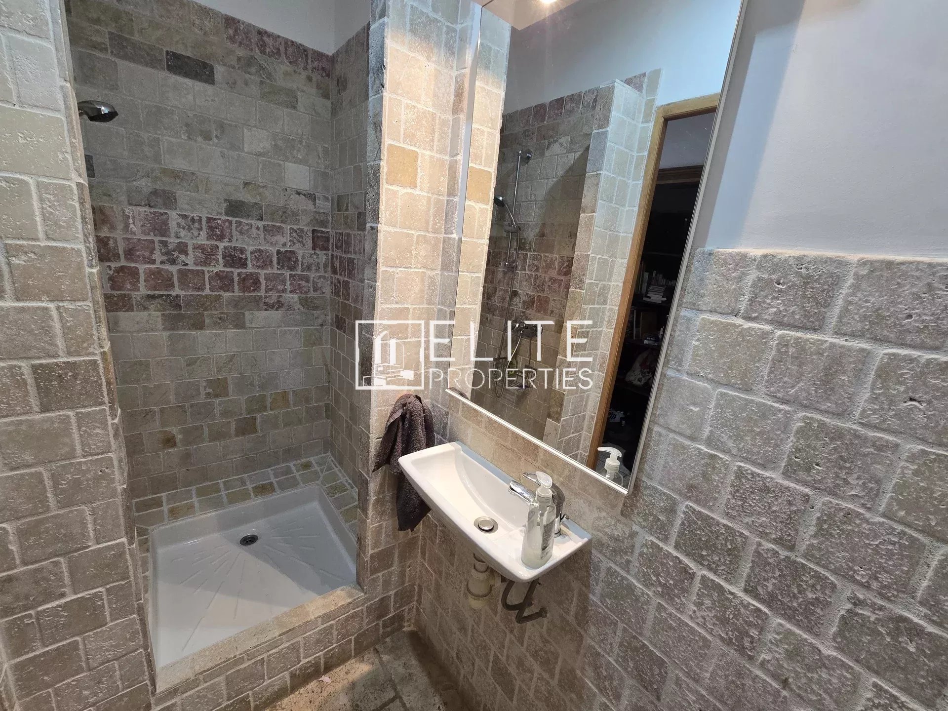 Salle de bain avec douche en mosaïque et lavabo dans une maison à Saint-Vallier-de-Thiey.
