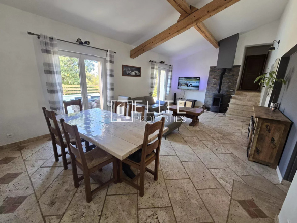 Intérieur d'une maison avec un salon et une salle à manger, éclairé par des fenêtres.