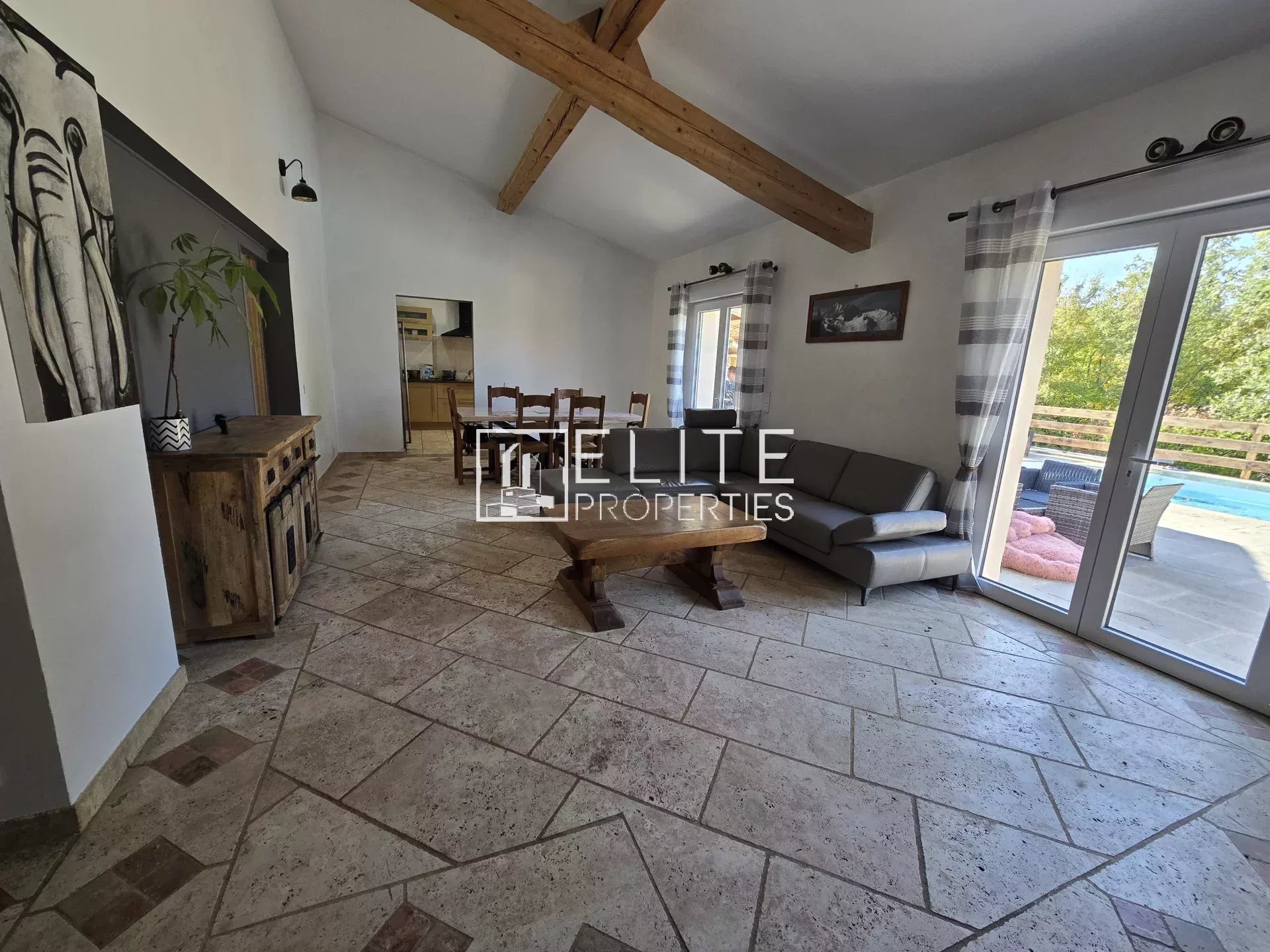 Intérieur d'une maison avec salon, table à manger et accès à la piscine.