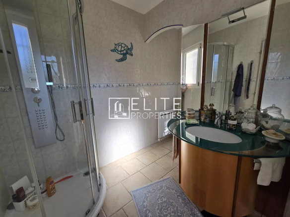Salle de bain moderne avec douche et meuble vasque dans une villa.