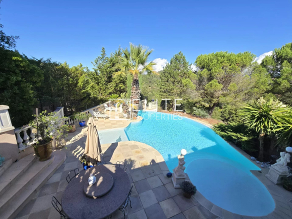 Vue d'une piscine à débordement entourée de verdure dans une villa.