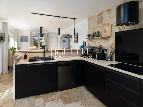 Cuisine moderne avec meubles noirs et plan de travail en pierre dans une villa à Fayence.