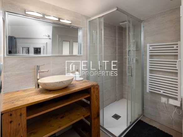 Salle de bain moderne avec douche, lavabo en bois et miroir, décorée dans des tons neutres.