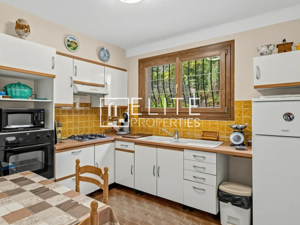 Kitchen of a house to be renovated in Mandelieu-la-Napoule, with white furniture and tiled floor.