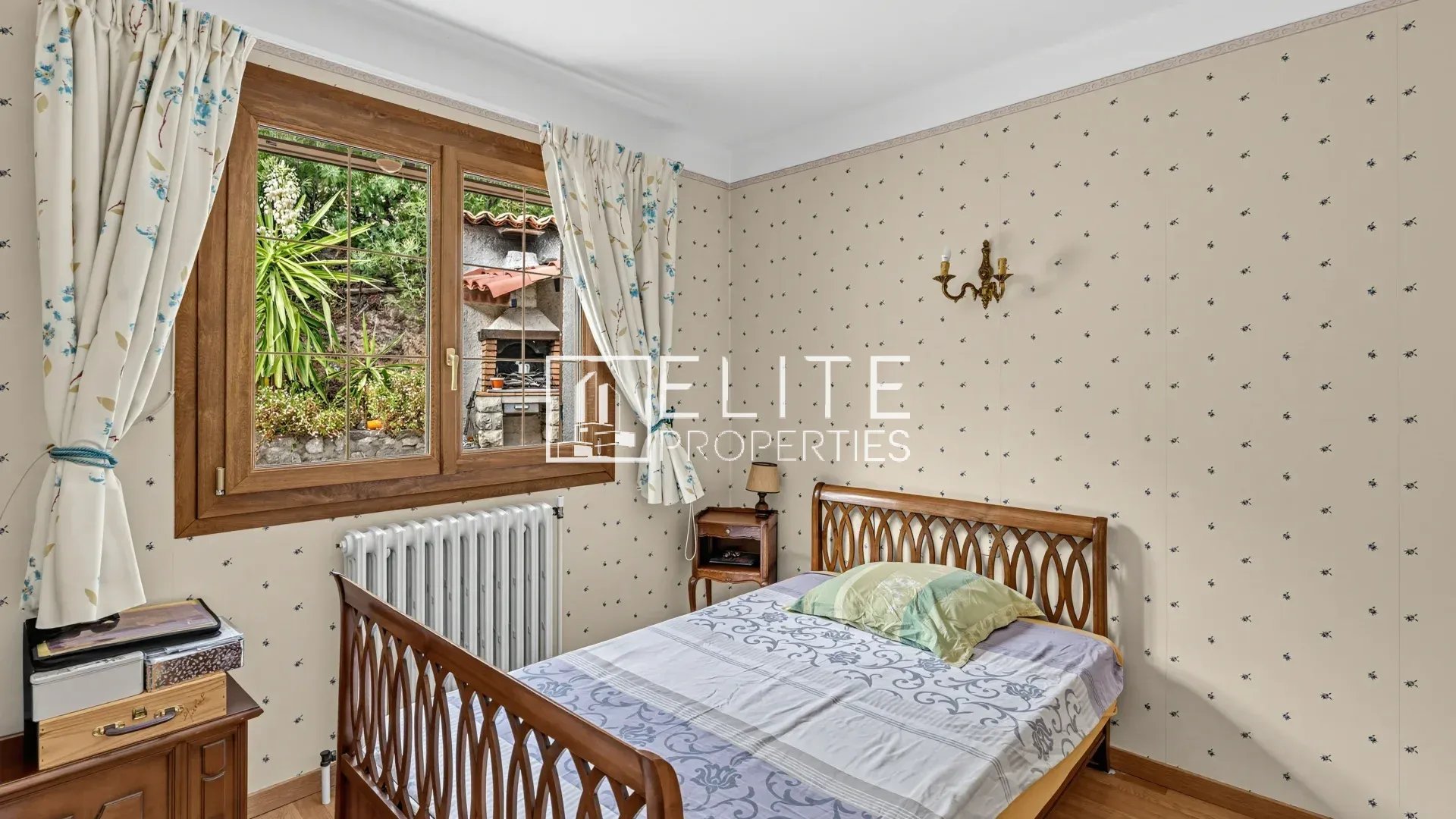 Room to renovate in Mandelieu-la-Napoule Room in a house to be renovated with a window overlooking a garden, wallpapered walls and wooden furniture.
