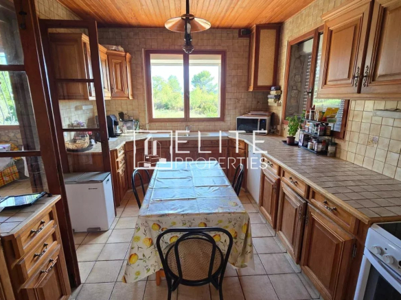 Cuisine d'une maison en pierre avec meubles en bois et table à manger, située à Mouans-Sartoux.
