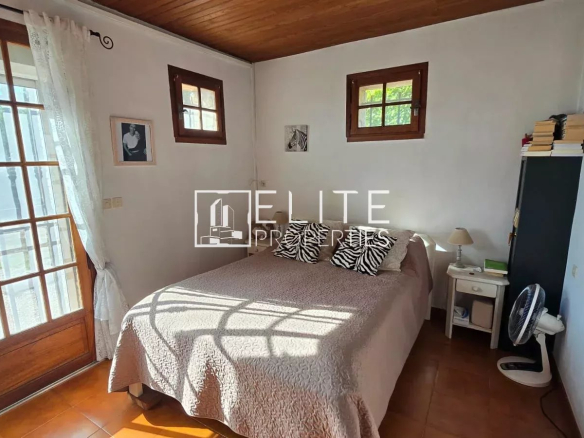 Chambre d'une maison en pierre avec lit et fenêtres donnant sur l'extérieur.