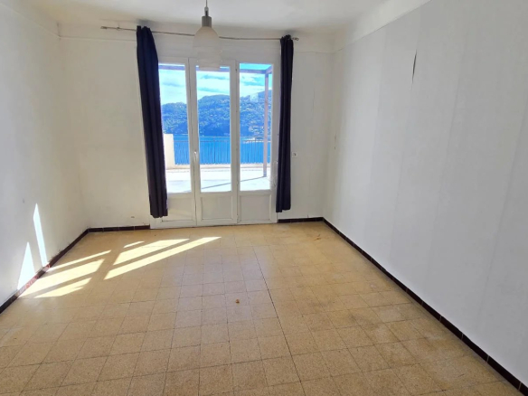 Intérieur d'une maison à rénover avec vue sur la mer, fenêtres ouvertes.