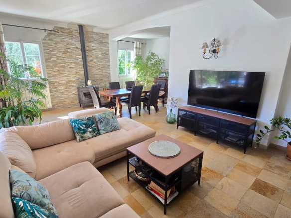 Intérieur d'une maison moderne avec un salon lumineux, un canapé et une télévision.