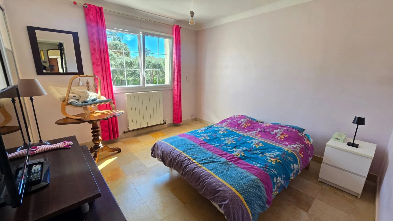 Chambre d’une maison à Mouans-Sartoux Chambre d'une maison avec lit, meuble TV et fenêtre laissant entrer la lumière.
