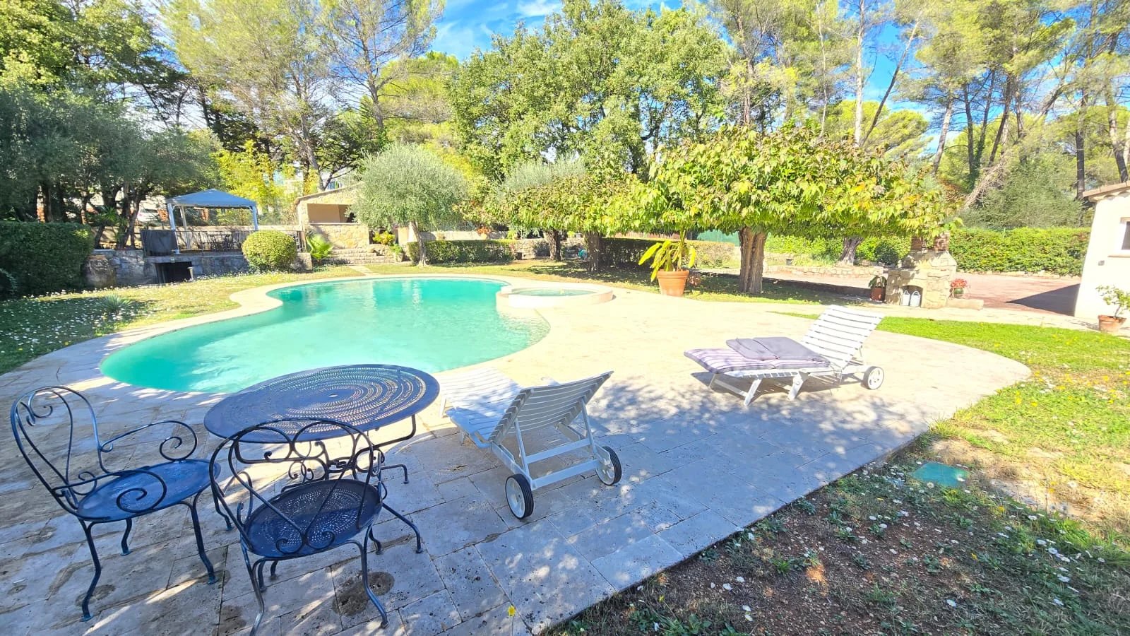 Espace extérieur avec piscine Piscine et espace extérieur d'une maison avec chaises longues et table, entourée d'arbres à Mouans-Sartoux.