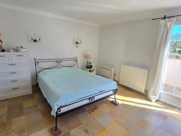 Chambre d'une maison avec lit, armoire et fenêtre donnant sur l'extérieur.