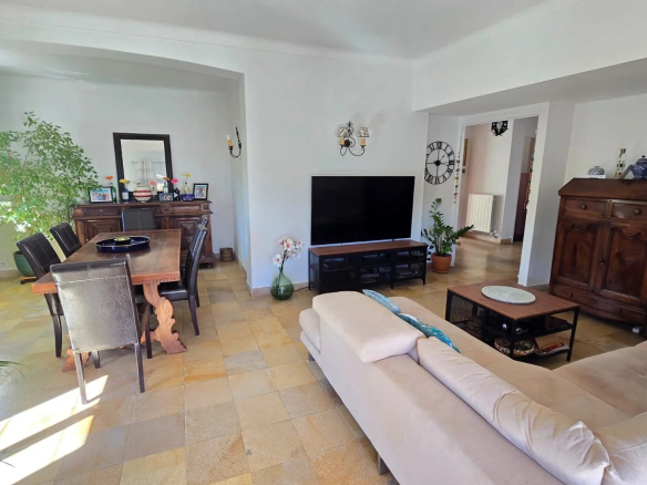 Intérieur d'une maison moderne avec salon et salle à manger, meubles en bois et télévision.