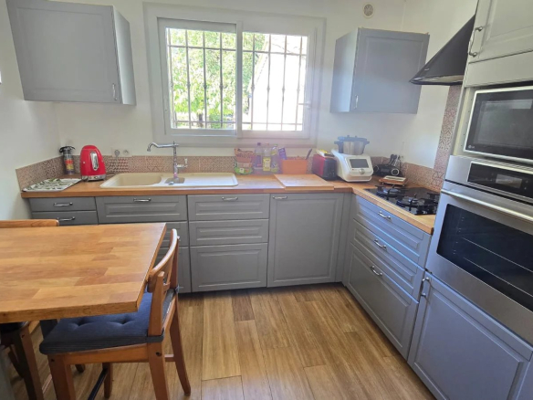 Cuisine moderne avec meubles gris et plan de travail en bois.