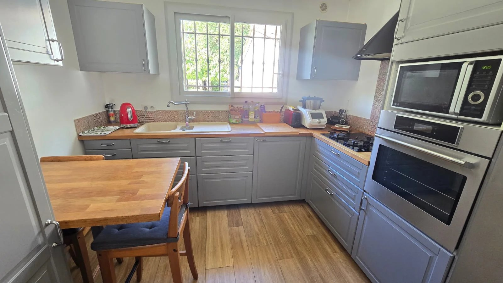 Cuisine de la maison à Mouans-Sartoux Cuisine moderne avec meubles gris et plan de travail en bois.
