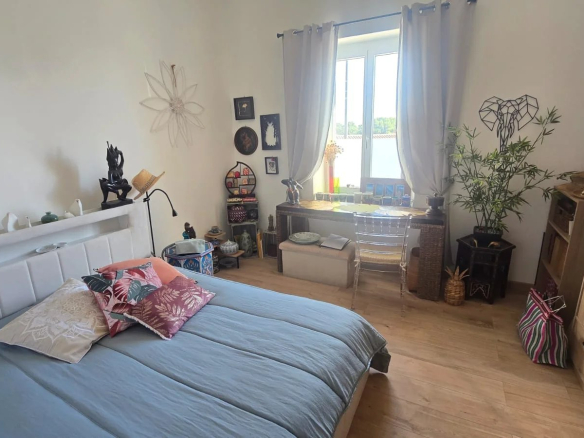 Chambre d'un logement avec décoration moderne et fenêtre laissant entrer la lumière.