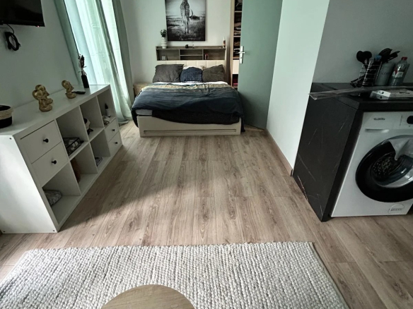 Chambre d'un logement avec lit, table basse et machine à laver.