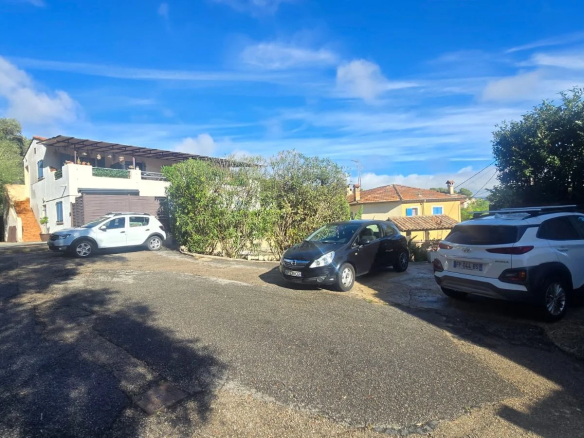Ensemble immobilier à Roquefort-les-Pins avec restaurant et logements, vue sur la cour et les voitures.