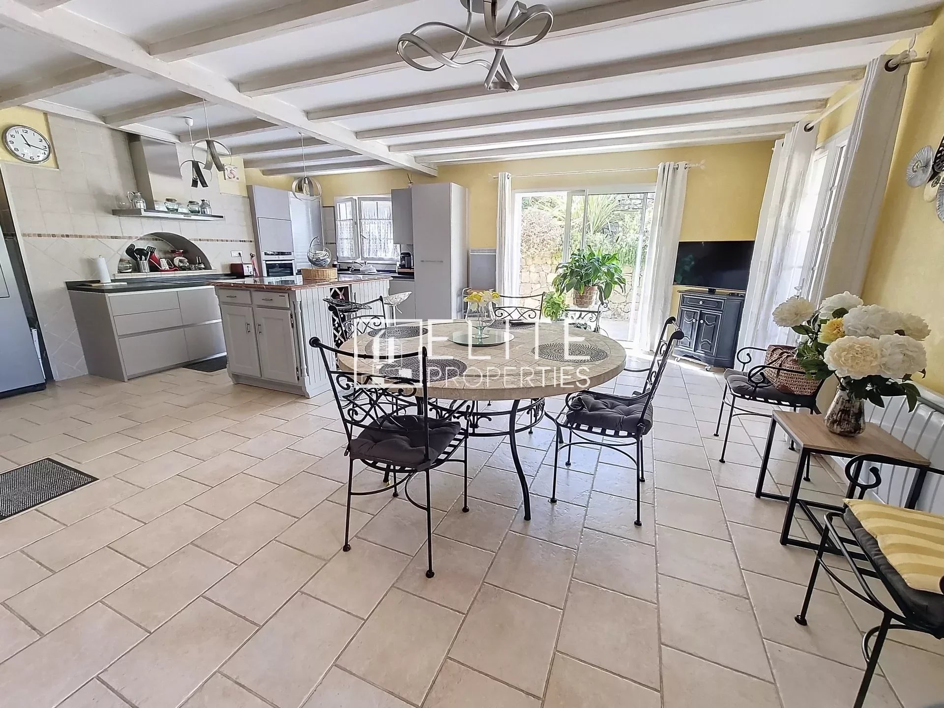 Intérieur d'une villa avec cuisine ouverte et salle à manger, mobilier en fer forgé, lumière naturelle
