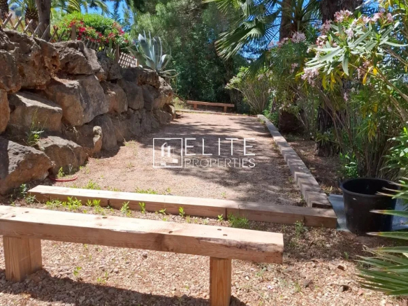 Allée en pierre avec bancs en bois dans un jardin arboré aux Adrets-de-l'Estérel.