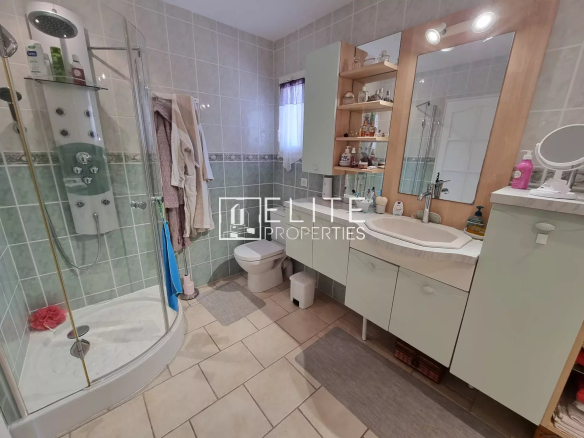 Salle de bain moderne avec douche, lavabo et toilettes, carrelage clair.
