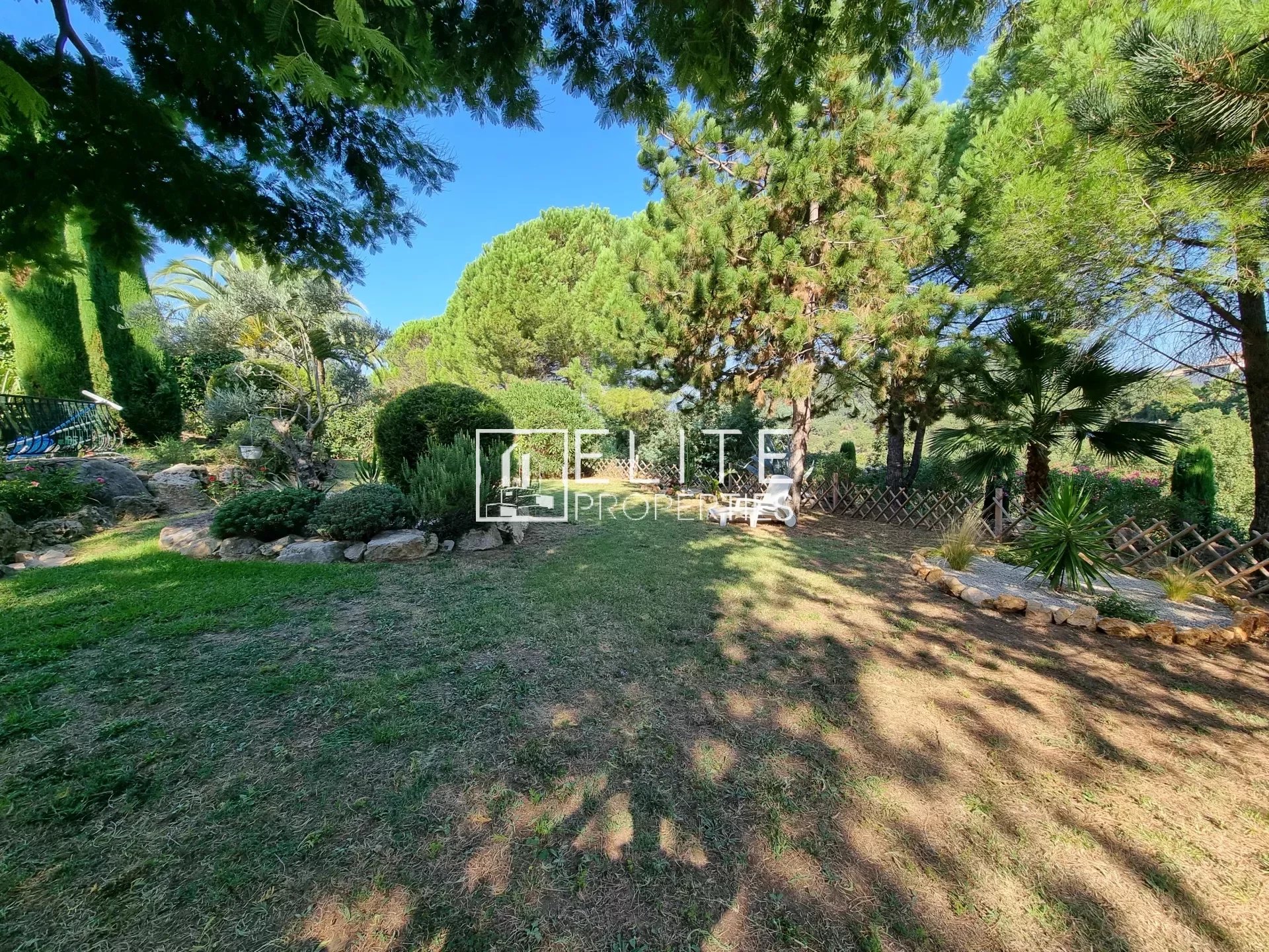 Jardin arboré d'une villa avec pelouse et arbres à Les Adrets-de-l'Estérel.