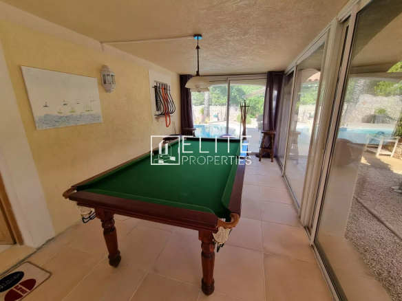 Salle de jeux avec table de billard dans une villa à Les Adrets-de-l'Estérel, piscine visible à l'extérieur.