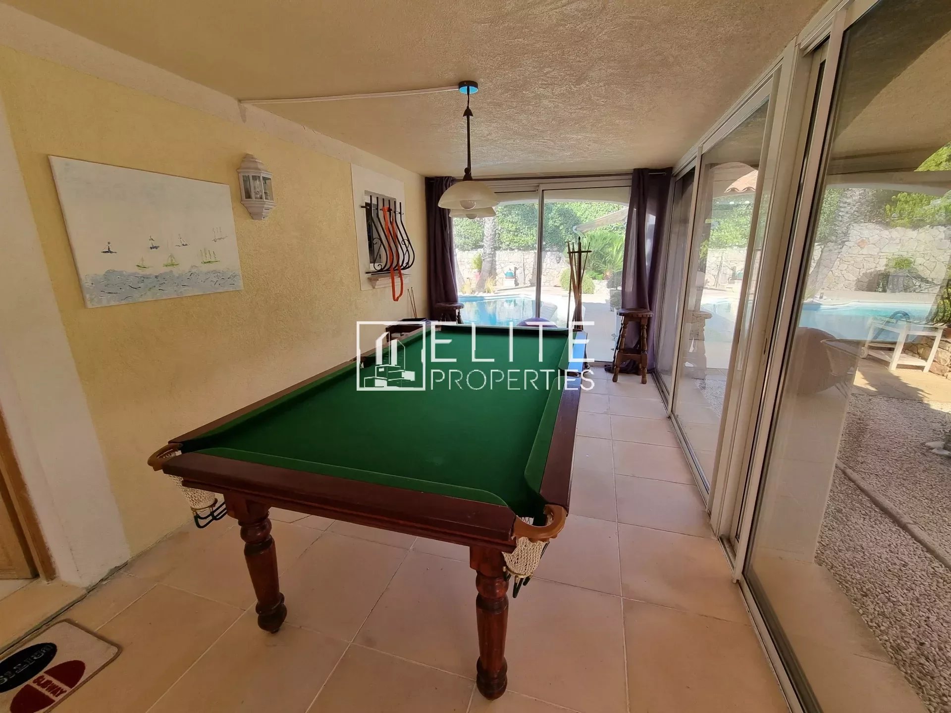 Salle de jeux avec table de billard dans une villa à Les Adrets-de-l'Estérel, piscine visible à l'extérieur.
