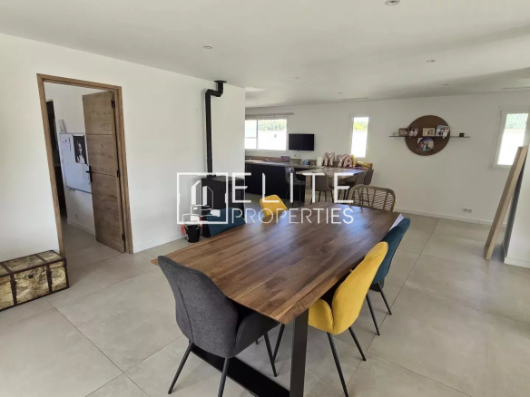 Intérieur d'une maison rénovée avec une grande table à manger et un espace cuisine ouvert.