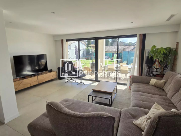 Intérieur d'une maison rénovée avec un salon moderne et lumineux, fenêtres donnant sur le jardin.