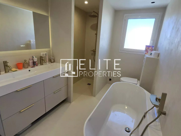 Salle de bain moderne avec baignoire et double vasque dans une maison rénovée à Grasse.