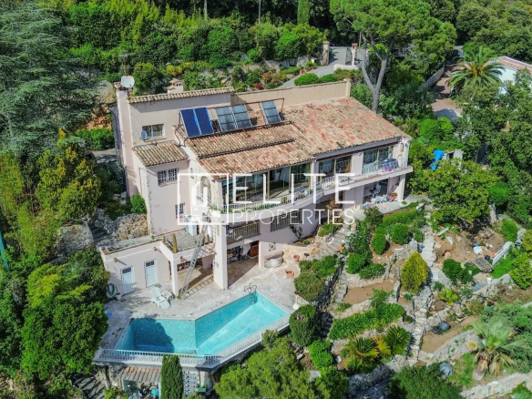 Vue aérienne d'une villa à Grasse avec piscine et jardin, entourée de verdure.