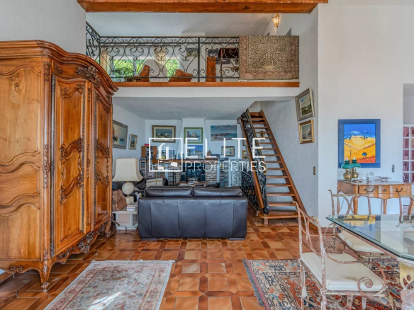 Intérieur d'une villa à Grasse avec un double séjour, une cheminée et un escalier en bois.