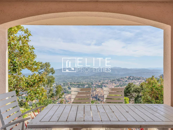 Vue panoramique depuis une terrasse avec une table et des chaises, surplombant Grasse et la mer.