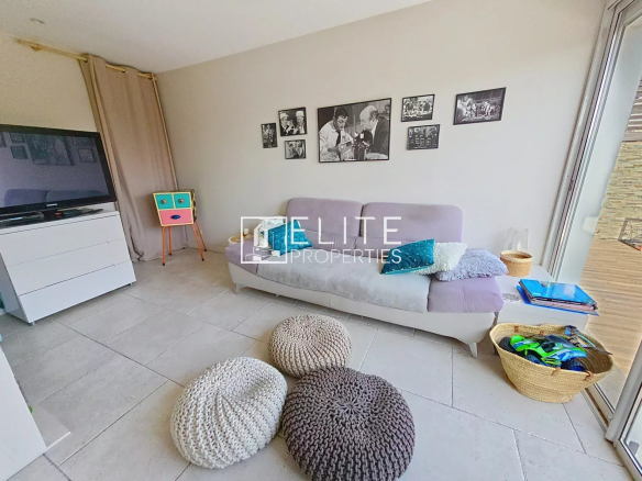 Living room of a house in Cannes, with a sofa, poufs and wall decorations.