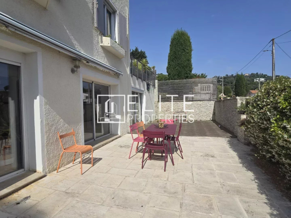 Terrace of a house with garden furniture, overlooking a wooded outdoor area.